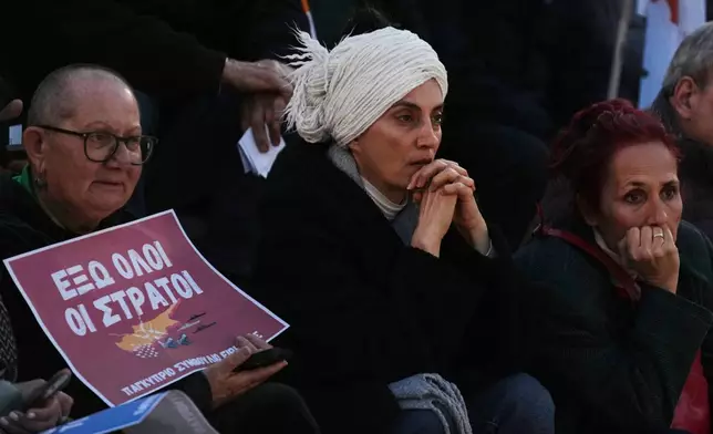 A protester holds a sign that reads in Greek "Get all the armies out" during an anti-war rally in the southern city of Limassol, Cyprus, Tuesday, March 3, 2026. (AP Photo/Petros Karadjias)
