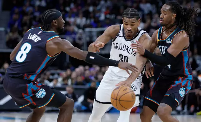 Brooklyn Nets guard Ochai Agbaji (30) tries to drive to the basket between Detroit Pistons guards Caris LeVert (8) and Daniss Jenkins, right, during the first half of an NBA basketball game Saturday, March 7, 2026, in Detroit. (AP Photo/Duane Burleson)