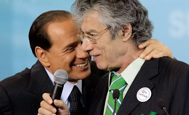 Northern League leader Umberto Bossi is embraced by Italian premier Silvio Berlusconi, left, at a rally to support the candidature of Letizia Moratti to mayor of Milan, in this northern Italian city, May 7, 2006. Bossi died at the age of 84 on Thursday, March 19, 2026. (AP Photo/Antonio Calanni, File)