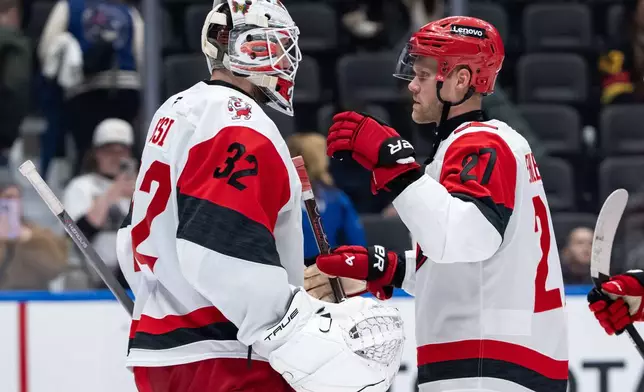 Carolina Hurricanes goaltender Brandon Bussi (32) and Nikolaj Ehlers (27) celebrate after defeating the Vancouver Canucks during the third period of an NHL hockey game in Vancouver, on Wednesday, March 4, 2026. (Ethan Cairns/The Canadian Press via AP)