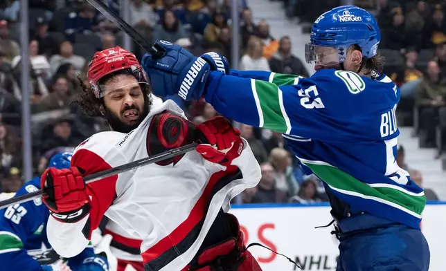 Vancouver Canucks' Teddy Blueger (53) hits Carolina Hurricanes' Jalen Chatfield (5) during the third period of an NHL hockey game in Vancouver, on Wednesday, March 4, 2026. (Ethan Cairns/The Canadian Press via AP)