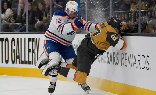 Edmonton Oilers right wing Vasily Podkolzin (92) checks Vegas Golden Knights defenseman Shea Theodore (27) into the boards during the third period of an NHL hockey game Sunday, March 8, 2026, in Las Vegas. (AP Photo/John Locher)