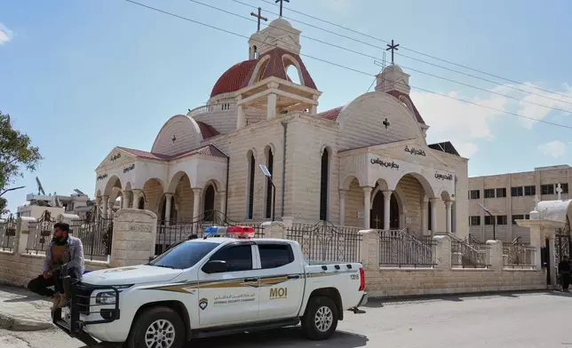 A member of Syria's Internal Security Forces sits on a vehicle parked outside a church in the predominantly Christian town of Al-Suqaylabiyah, west of Hama, Syria, Saturday, March 28, 2026, following overnight violence. (AP Photo/Omar Albam)