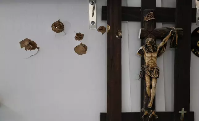 Bullet holes mark a wall next to a crucifix following overnight violence in the predominantly Christian town of Al-Suqaylabiyah, west of Hama, Syria, Saturday, March 28, 2026. (AP Photo/Omar Albam)