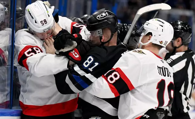 Ottawa Senators center Tim Stützle (18) grabs Tampa Bay Lightning defenseman Erik Cernak (81) as Cernak and defenseman Carter Yakemchuk (58) fight during the second period of an NHL hockey game Saturday, March 28, 2026, in Tampa, Fla. (AP Photo/Jason Behnken)