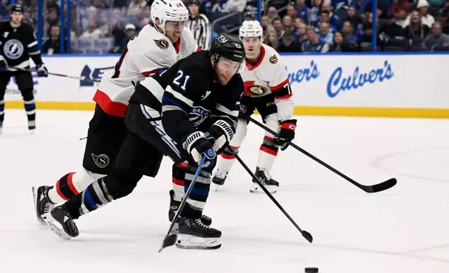 Tampa Bay Lightning center Brayden Point (21) and Ottawa Senators center Dylan Cozens (24) battle for the puck during the second period of an NHL hockey game Saturday, March 28, 2026, in Tampa, Fla. (AP Photo/Jason Behnken)
