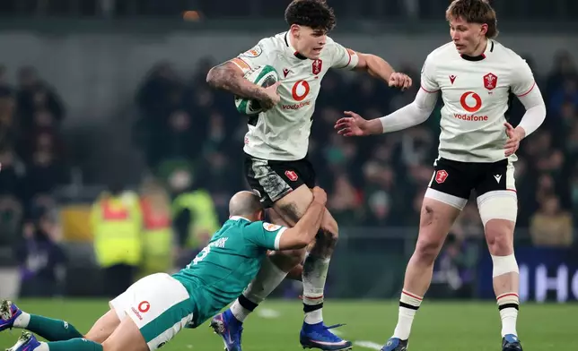Wales' Eddie James, center, is tackled by Ireland's Jamison Gibson-Park during a Six Nations rugby union match between Ireland and Wales in Dublin, Ireland, Friday, March 6, 2026. (AP Photo/Peter Morrison)