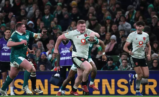 Wales' Rhys Carre, center, breaks through to score his team's first try during a Six Nations rugby union match between Ireland and Wales in Dublin, Ireland, Friday, March 6, 2026. (AP Photo/Peter Morrison)