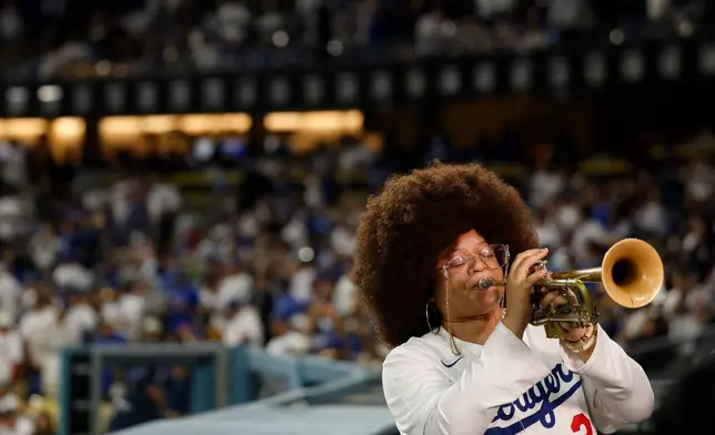 Tatiana Tate plays the trumpet as Los Angeles Dodgers relief pitcher Edwin Diaz runs out to field in between the eighth and ninth innings of a baseball game Friday, March 27, 2026, in Los Angeles. (AP Photo/Caroline Brehman)