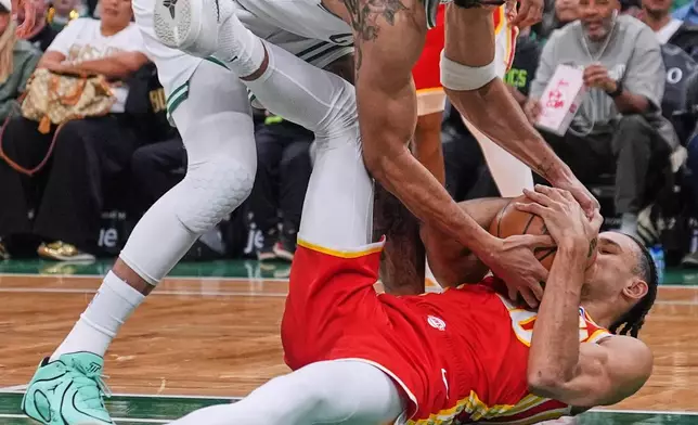 Boston Celtics forward Jayson Tatum, top, wrestles for the ball with Atlanta Hawks forward Zaccharie Risacher, bottom, during the first half of an NBA basketball game, Friday, March 27, 2026, in Boston. (AP Photo/Charles Krupa)