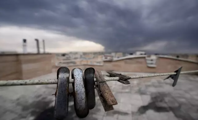 Clothes clips covered in soot from burned fuel are seen as smoke from a U.S.-Israeli strike on an oil facility late Saturday lingers in the cloudy sky over Tehran, Iran, Sunday, March 8, 2026. (AP Photo/Vahid Salemi)