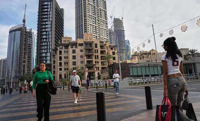 People cross a street in downtown Dubai, United Arab Emirates, Saturday, March 7, 2026. (AP Photo/ Fatima Shbair)