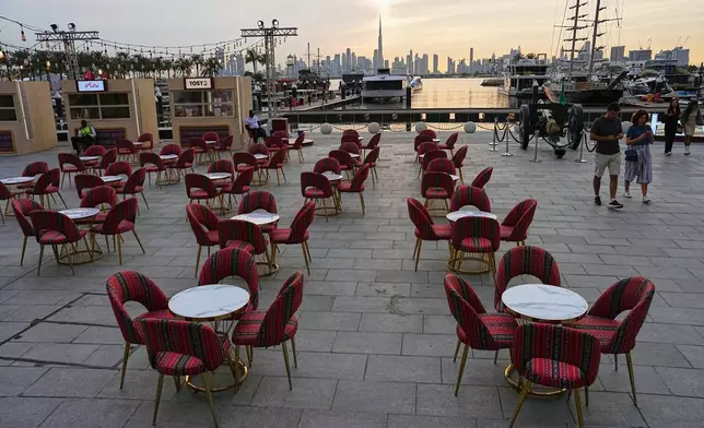 People walk past an outdoor empty restaurant at Dubai Creek Harbour in Dubai, United Arab Emirates, Wednesday, March 11, 2026. (AP Photo/Fatima Shbair)