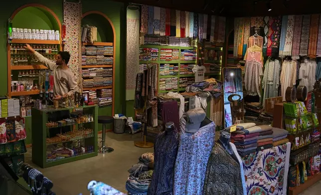 A vendor arranges products inside a shop at the empty Al Seef market, next to the historic Al Fahidi neighborhood along Dubai Creek, one of the main tourist areas of Dubai, United Arab Emirates, Friday, March 13, 2026, as tourism slows amid regional tensions linked to the Iran war. (AP Photo/Fatima Shbair)