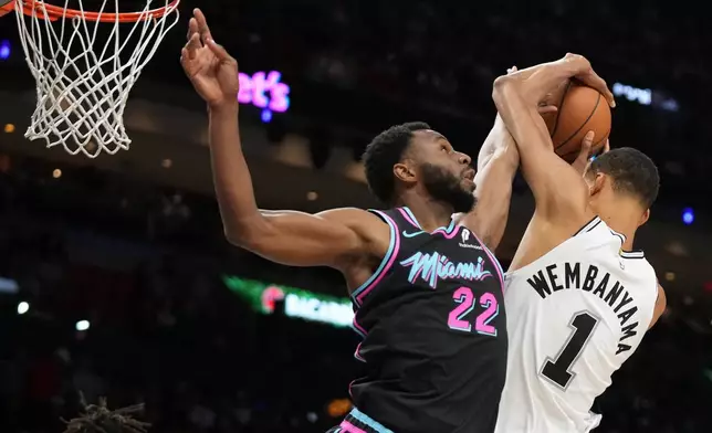 Miami Heat forward Andrew Wiggins (22) goes for a rebound against San Antonio Spurs forward Victor Wembanyama (1) during the second half of an NBA basketball game, Monday, March 23, 2026, in Miami. (AP Photo/Lynne Sladky)