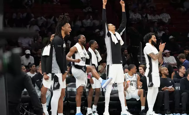 San Antonio Spurs forward Harrison Barnes (40) and forward Victor Wembanyama, second from right, reacts from the bench with their teammates during the second half of an NBA basketball game against the Miami Heat, Monday, March 23, 2026, in Miami. (AP Photo/Lynne Sladky)