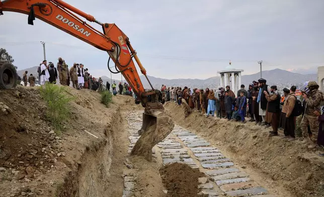 An excavator covers the graves during a second mass funeral for victims killed in an airstrike that hit a drug rehabilitation center earlier this month, in Kabul, Afghanistan, Thursday, March 26, 2026. (AP Photo/Siddiqullah Alizai)
