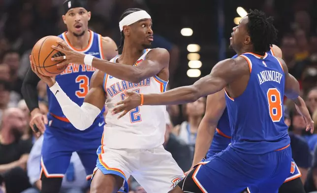 Oklahoma City Thunder guard Shai Gilgeous-Alexander (2) keeps the ball away from New York Knicks forward Og Anunoby (8) and guard Josh Hart (3) during the first half of an NBA basketball game Sunday, March 29, 2026, in Oklahoma City. (AP Photo/Nate Billings)