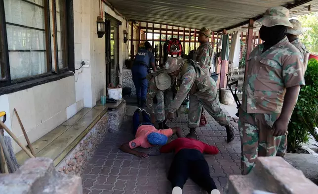 South African National Defense Force officers search suspects, in the Westbury township of Johannesburg, South Africa, Wednesday, March 11, 2026. (AP Photo/Themba Hadebe)