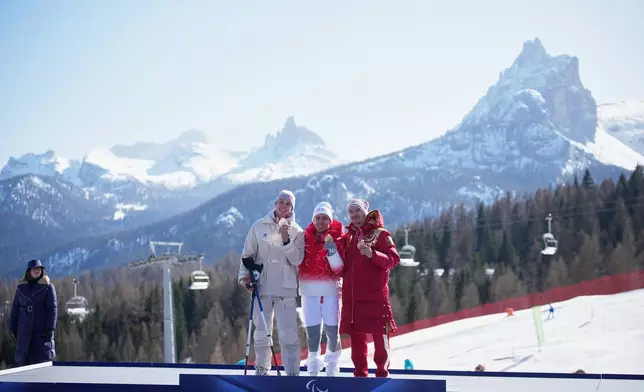 Silver medalist Arthur Bauchet, of France, from left, gold medalist Robin Cuche, of Switzerland, and bronze medalist Aleksei Bugaev, of Russia, pose on the podium of the alpine skiing men's downhill standing competition at the 2026 Winter Paralympics, in Cortina d'Ampezzo, Italy, Saturday, March 7, 2026. (AP Photo/Emilio Morenatti)