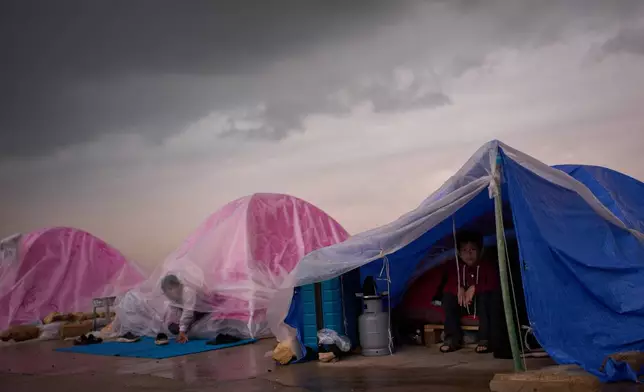Children displaced from Beirut's southern suburb of Dahiyeh shelter from the rain inside their tents along the coast in Beirut, Lebanon, Thursday, March 26, 2026. (AP Photo/Emilio Morenatti)