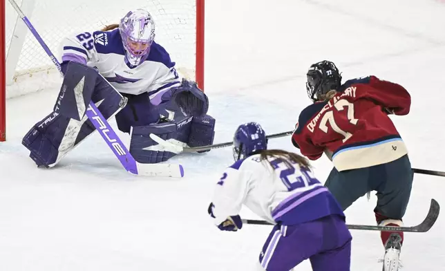 Montreal Victoire's Jade Downie-Landry (77) shoots against Minnesota Frost goaltender Nicole Hensley (29) as Frost's Natalie Buchbinder (22) defends during third-period PWHL hockey game action in Laval, Quebec, Sunday, March 1, 2026. (Graham Hughes/The Canadian Press via AP)