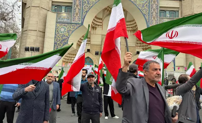 A group of men wave Iranian flags as they attend a demonstration in support of the government and against U.S. and Israeli strikes in Tehran, Iran, Saturday, Feb. 28, 2026. (AP Photo/Vahid Salemi)