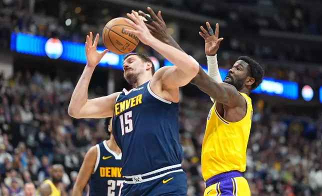 Denver Nuggets center Nikola Jokić, left, fights for control of a rebound with Los Angeles Lakers center Deandre Ayton in the first half of an NBA basketball game Thursday, March 5, 2026, in Denver. (AP Photo/David Zalubowski)