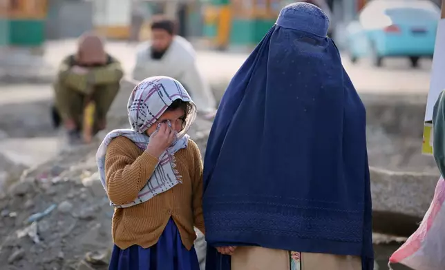 A little girl and a woman watch as rescue workers and officials inspect the site of a late-Monday airstrike at a drug rehabilitation hospital in Kabul, Afghanistan, Tuesday, March 17, 2026. (AP Photo/Siddiqullah Alizai)