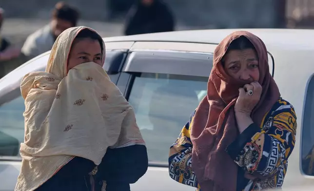 Two women watch as rescue workers and officials inspect the site of a late-Monday airstrike at a drug rehabilitation hospital in Kabul, Afghanistan, Tuesday, March 17, 2026. (AP Photo/Siddiqullah Alizai)