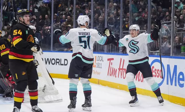 Seattle Kraken's Bobby McMann, right, and Shane Wright celebrate McMann's goal as Vancouver Canucks' Aatu Raty (54) looks on during the first period of an NHL hockey game, in Vancouver, on Saturday, March 14, 2026. (Darryl Dyck/The Canadian Press via AP)