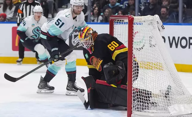 Vancouver Canucks goalie Nikita Tolopilo (60) allows a goal to Seattle Kraken's Bobby McMann, back left, as Shane Wright (51) watches during the first period of an NHL hockey game, in Vancouver, on Saturday, March 14, 2026. (Darryl Dyck/The Canadian Press via AP)
