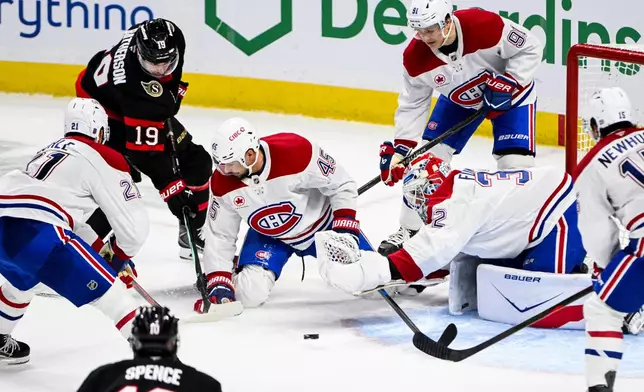 Montreal Canadiens goaltender Jacob Fowler (32) reaches out for the puck as Ottawa Senators' Drake Batherson (19) looks for a shot on goal opportunity during the third period of an NHL hockey game in Ottawa, Ontario, Wednesday, March 11, 2026. (Spencer Colby/The Canadian Press via AP)