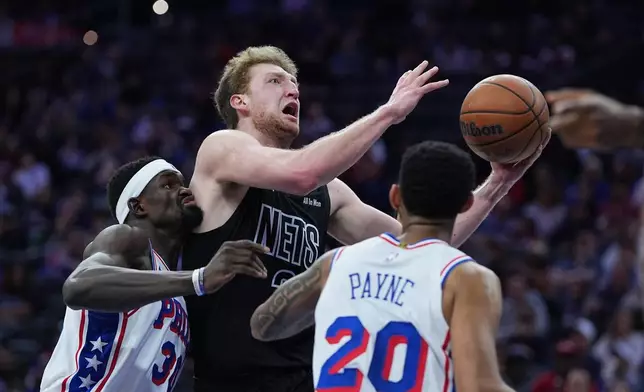 Brooklyn Nets' Danny Wolf, center, shoots between Philadelphia 76ers' Adem Bona, left, and Cameron Payne (20) during the first half of an NBA basketball game Saturday, March 14, 2026, in Philadelphia. (AP Photo/Matt Rourke)