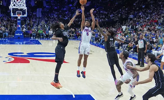Philadelphia 76ers' Quentin Grimes (5) shotos between Brooklyn Nets' Ziaire Williams, and Terance Mann (14) during the first half of an NBA basketball game Saturday, March 14, 2026, in Philadelphia. (AP Photo/Matt Rourke)