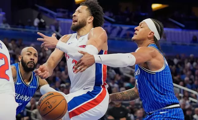 Detroit Pistons guard Cade Cunningham, center, loses control of the ball as he tries to go between Orlando Magic guard Jevon Carter, left, and forward Paolo Banchero during the first half of an NBA basketball game, Sunday, March 1, 2026, in Orlando, Fla. (AP Photo/John Raoux)