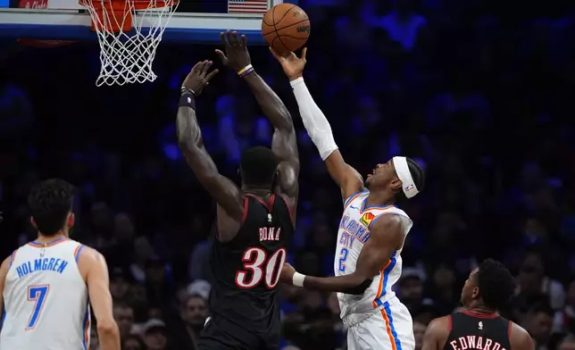 Oklahoma City Thunder's Shai Gilgeous-Alexander (2) goes up for a shot against Philadelphia 76ers' Adem Bona (30) during the first half of an NBA basketball game Monday, March 23, 2026, in Philadelphia. (AP Photo/Matt Slocum)