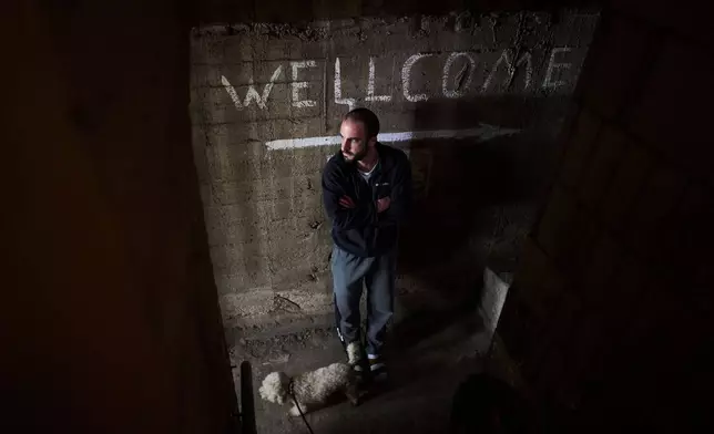 A man takes cover in a bomb shelter underneath a residential building as air raid sirens warn of incoming missile strikes from Iran in Ramat Gan, Israel, Sunday, March 22, 2026. (AP Photo/Oded Balilty)