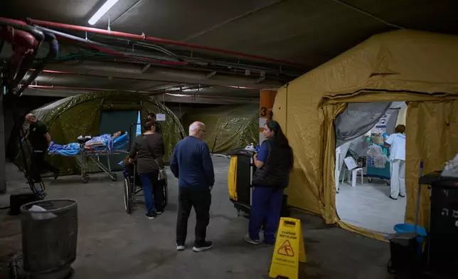 Medical staff transfer patients in a temporary emergency ward set up in a parking garage used as a shelter beneath Sheba Medical Center in Ramat Gan, Israel, Tuesday, March 17, 2026. (AP Photo/Oded Balilty)