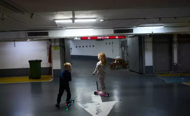 Children play in an underground parking garage where people spend the night as a precaution against possible Iranian missile attacks in Tel Aviv, Israel, Saturday, March 14, 2026. (AP Photo/Oded Balilty)