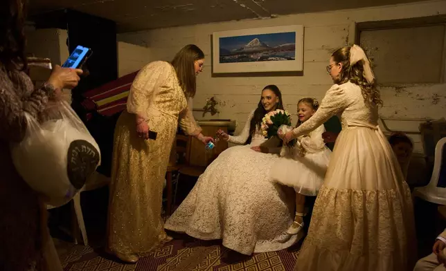 A bride and her family sit in a bomb shelter after an alert warning of missiles fired from Iran toward central Israel interrupted their wedding photo shoot in a nearby park in Ramat Gan, Israel, Thursday, March 19, 2026. (AP Photo/Oded Balilty)