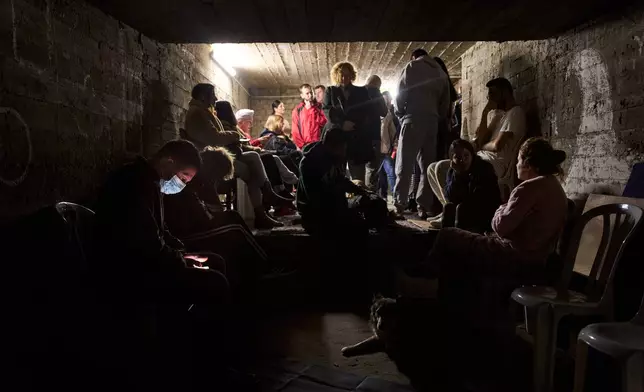 People gather in a bomb shelter as air raid sirens warn of incoming missiles from Iran in Ramat Gan, Israel, Sunday, March 22, 2026. (AP Photo/Oded Balilty)