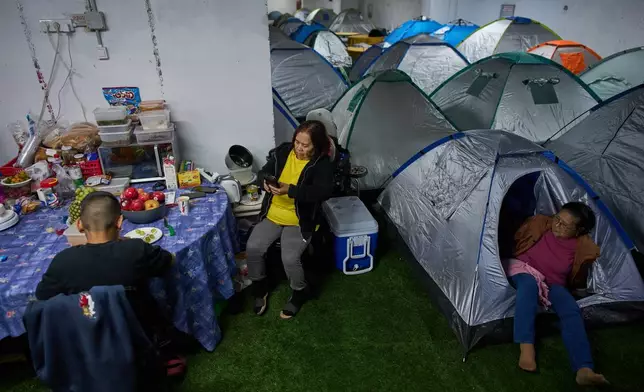 People sit around a makeshift dinner table with groceries beside tents as they take shelter beneath Tel Aviv's central bus station as a precaution against possible Iranian missile attacks, Thursday, March 12, 2026. (AP Photo/Oded Balilty)