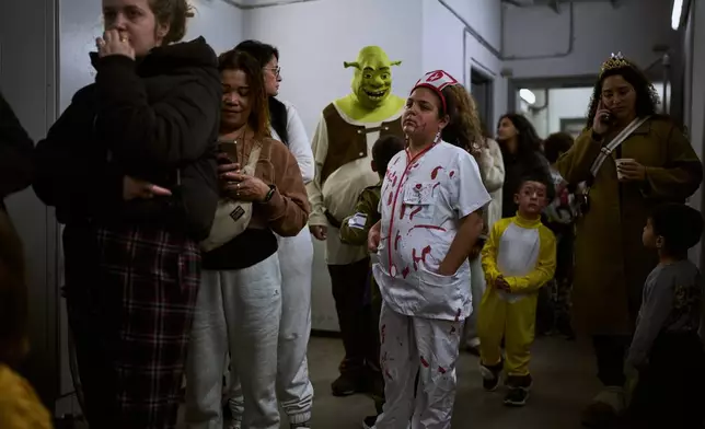People, some wearing costumes for the Jewish holiday of Purim, gather in an underground metro station used as a shelter against possible Iranian missile attacks in Ramat Gan, Israel, Monday, March 2, 2026. (AP Photo/Oded Balilty)
