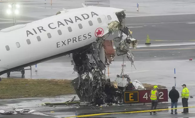 Officials investigate the site, Monday, March 23, 2026, where an Air Canada jet came to rest after colliding with a Port Authority firetruck at LaGuardia Airport, shortly after landing Sunday night in New York. (AP Photo/Seth Wenig)