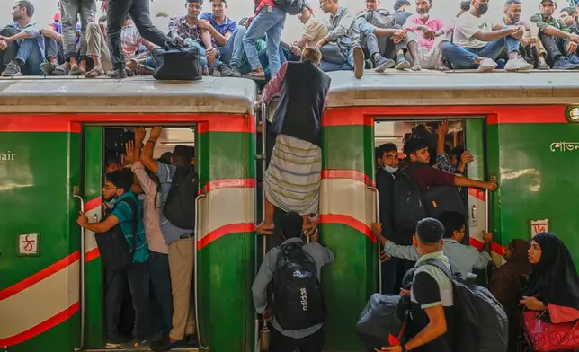 Homebound travelers scramble to board a train at Kamalapur Railway Station, joining the massive annual exodus to celebrate Eid al-Fitr, in Dhaka, Bangladesh, Wednesday, March 18, 2026. (AP Photo/Mahmud Hossain Opu)