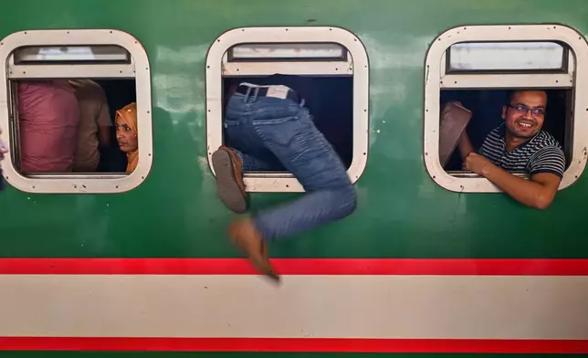 Homebound travelers scramble to board a train at Kamalapur Railway Station, joining the massive annual exodus to celebrate Eid al-Fitr, in Dhaka, Bangladesh, Wednesday, March 18, 2026. (AP Photo/Mahmud Hossain Opu)