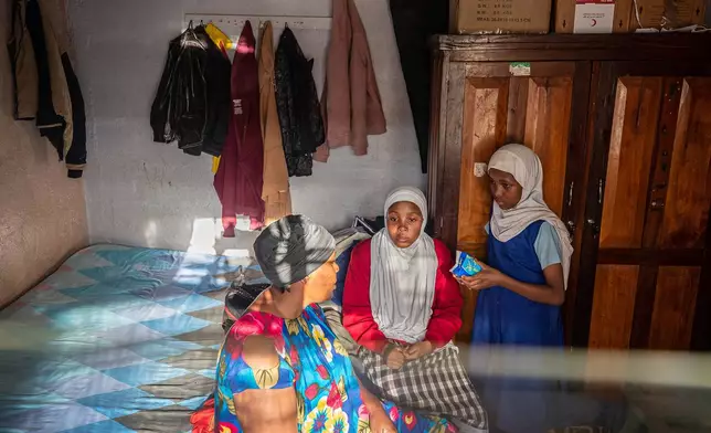 Alima Nasur talks to her daughters, Salama Halima, 13, center, and Buthaina Halima, 11, right, about menstrual health inside their home in the Kibera informal settlement on the outskirts of Nairobi, Kenya, Feb. 12, 2026. (AP Photo/Atieno Muyuyi)