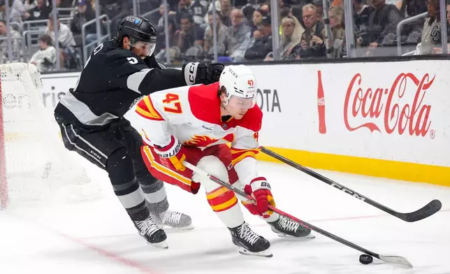 Calgary Flames center Connor Zary, right, moves the puck against Los Angeles Kings defenseman Cody Ceci during the first period of an NHL hockey game Saturday, Feb. 28, 2026 in Los Angeles. (AP Photo/Ryan Sun)
