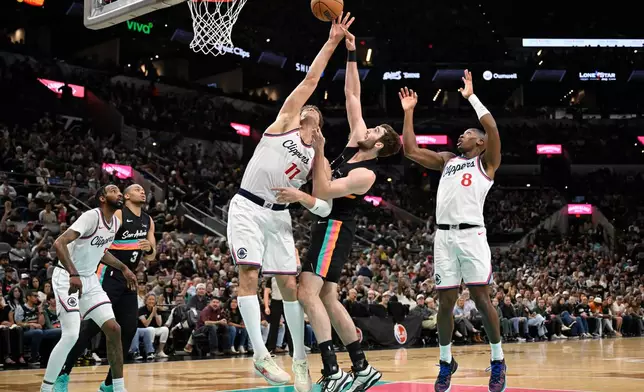San Antonio Spurs center Luke Kornet and Los Angeles Clippers center Brook Lopez (11) fight for possession during the first half of an NBA basketball game, Friday, March 6, 2026, in San Antonio. (AP Photo/Darren Abate)